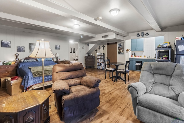 bedroom with beamed ceiling and light hardwood / wood-style floors