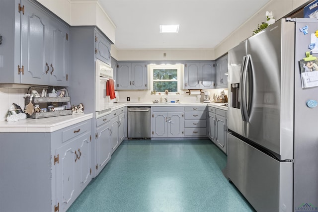 kitchen featuring appliances with stainless steel finishes, tasteful backsplash, and gray cabinets