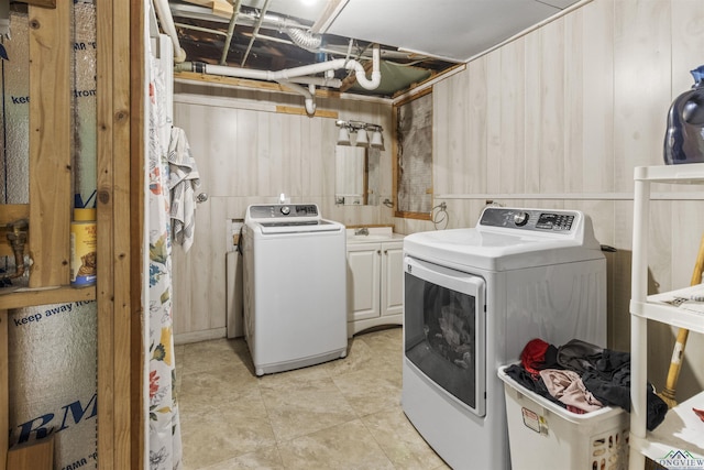 laundry room featuring washer and clothes dryer, light tile patterned flooring, and cabinets