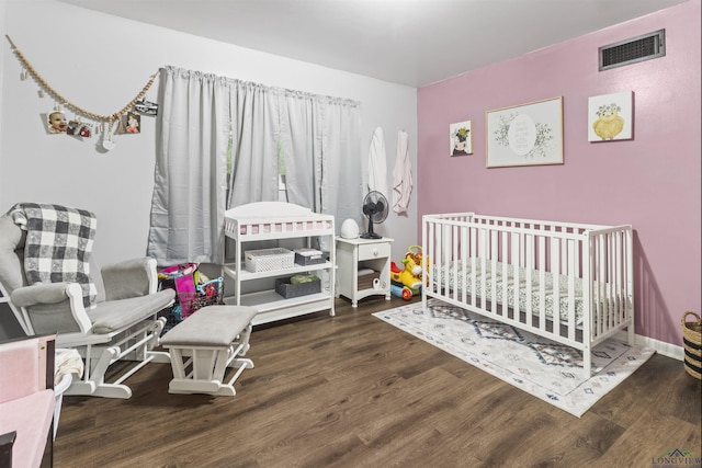 bedroom with dark wood-type flooring and a nursery area