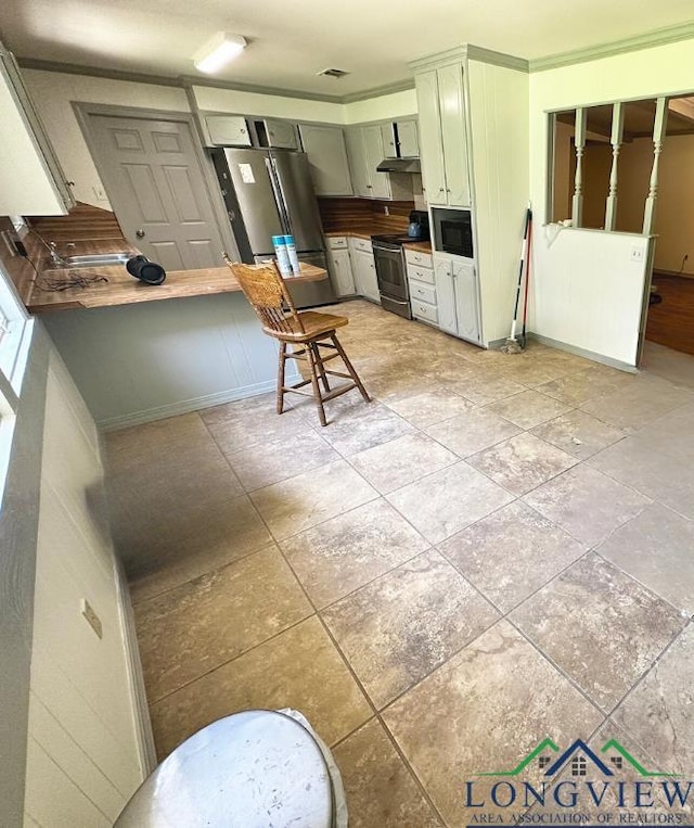 kitchen with a kitchen bar, stainless steel appliances, and ornamental molding