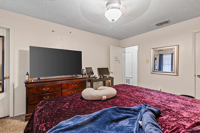 carpeted bedroom with visible vents, a textured ceiling, and a ceiling fan