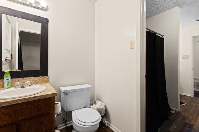 full bathroom featuring toilet, a textured ceiling, wood finished floors, baseboards, and vanity