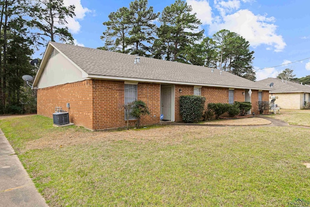 single story home with a front yard, brick siding, central AC, and roof with shingles