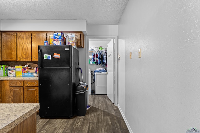 kitchen with dark wood-style floors, separate washer and dryer, brown cabinets, and freestanding refrigerator