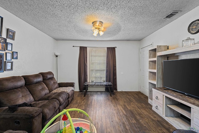 living room featuring visible vents, a ceiling fan, a textured ceiling, wood finished floors, and baseboards