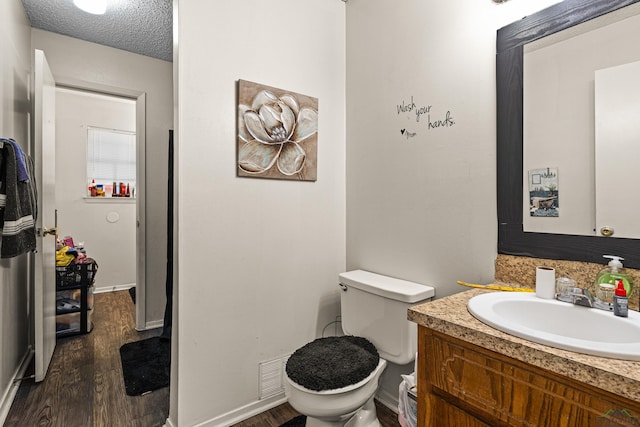 bathroom featuring visible vents, toilet, a textured ceiling, wood finished floors, and vanity