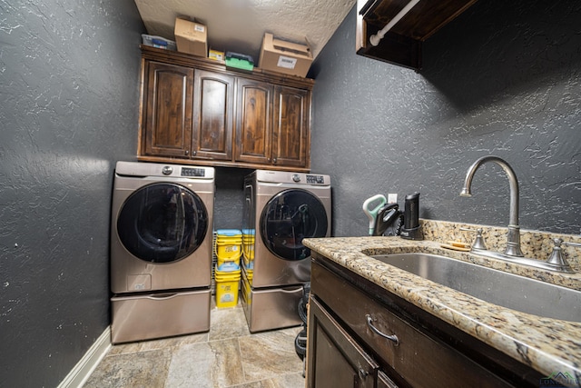 washroom featuring washer and dryer, a textured ceiling, cabinets, and sink