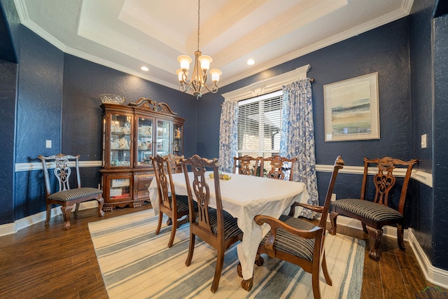 dining room with hardwood / wood-style flooring, an inviting chandelier, a tray ceiling, and crown molding