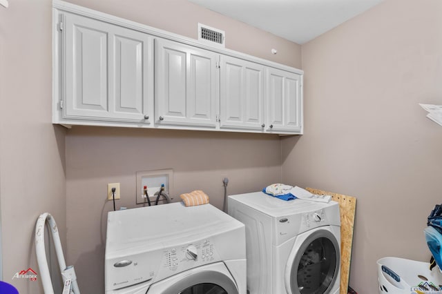 clothes washing area featuring cabinets and washing machine and dryer