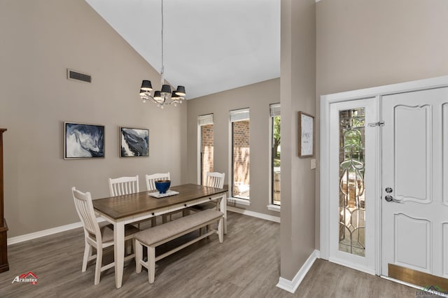 dining area with a chandelier, hardwood / wood-style flooring, and high vaulted ceiling