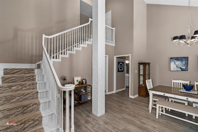 stairs featuring a chandelier, a towering ceiling, and wood-type flooring