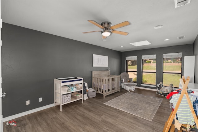 bedroom with ceiling fan, dark wood-type flooring, and a nursery area