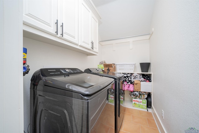 washroom with washer and clothes dryer, cabinets, and light tile patterned floors