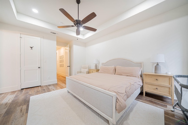 bedroom featuring hardwood / wood-style floors, ceiling fan, and a tray ceiling