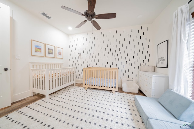 bedroom featuring a nursery area and ceiling fan