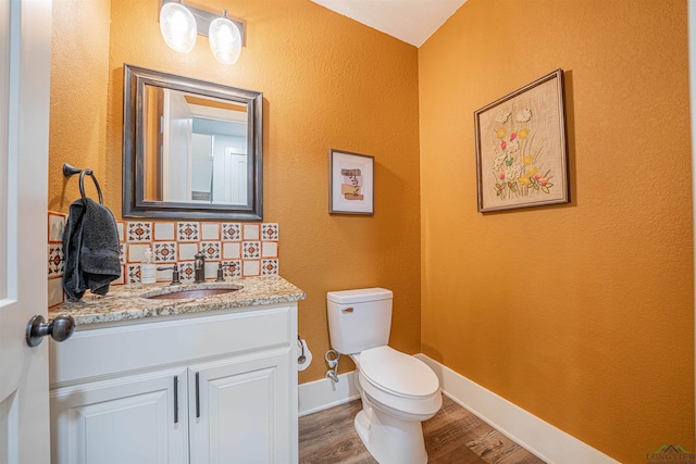 bathroom featuring hardwood / wood-style floors, vanity, toilet, and backsplash