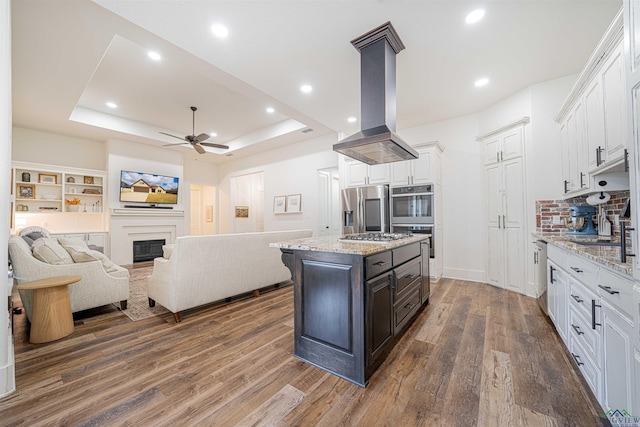 kitchen featuring white cabinets, a center island, island exhaust hood, and appliances with stainless steel finishes