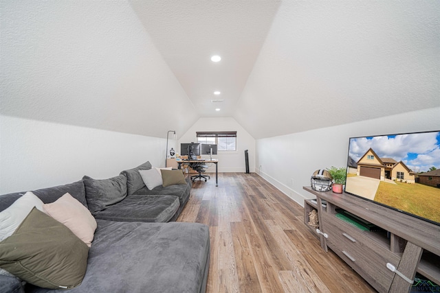 living room featuring light hardwood / wood-style floors, a textured ceiling, and vaulted ceiling