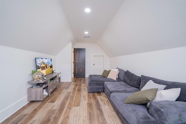 living room featuring lofted ceiling and hardwood / wood-style flooring