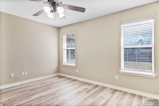 spare room with light wood-style flooring, a ceiling fan, and baseboards