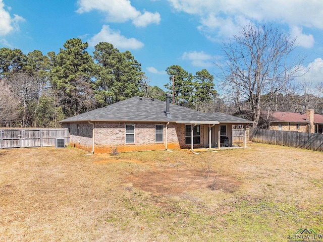 rear view of property with a lawn, central AC, brick siding, and fence