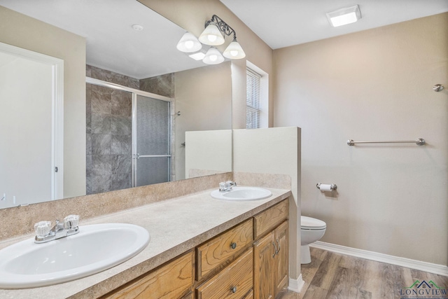 bathroom featuring a sink, wood finished floors, toilet, and a stall shower