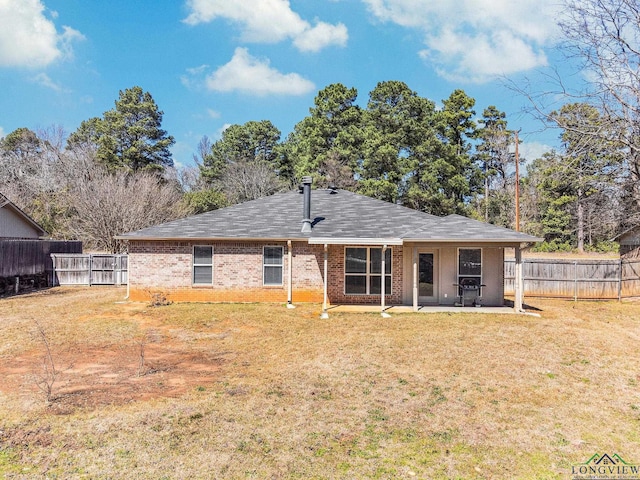 back of house with brick siding, a patio, a yard, and fence