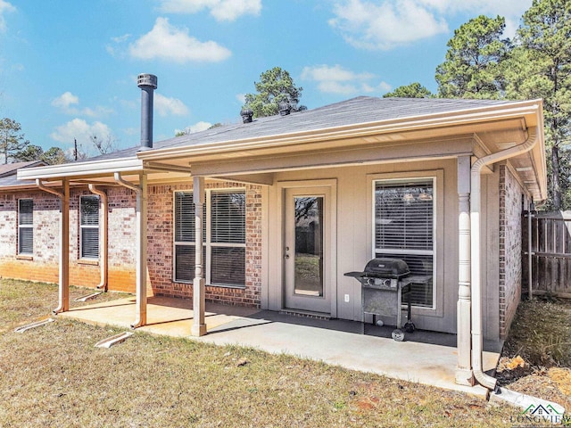 back of property featuring a patio area, a yard, brick siding, and fence