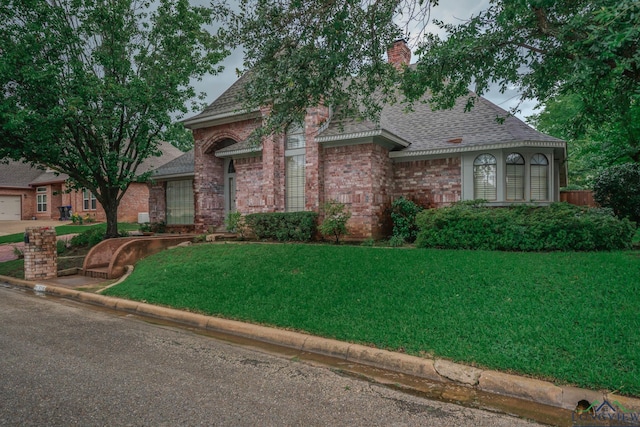 315 Tealwood Dr, Longview, TX 75605 - view of front of home with roof with shingles, a front yard, a chimney, and brick siding