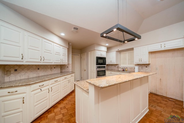 315 Tealwood Dr, Longview, TX 75605 - kitchen featuring stainless steel oven, black microwave, decorative backsplash, white cabinetry, and light stone counters