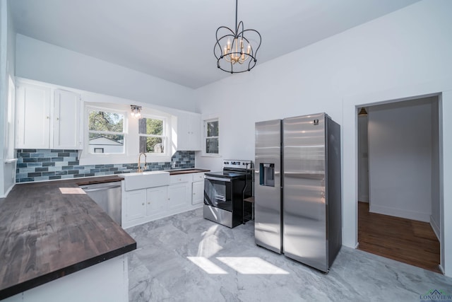 kitchen featuring an inviting chandelier, appliances with stainless steel finishes, decorative light fixtures, white cabinets, and sink