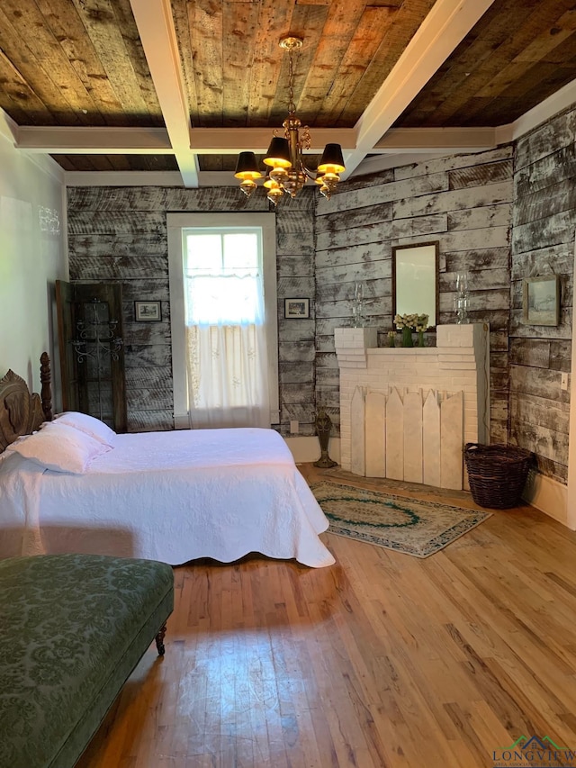 bedroom featuring hardwood / wood-style floors, wooden walls, beam ceiling, and an inviting chandelier