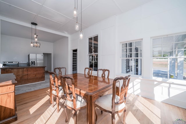 dining space with light wood-type flooring and an inviting chandelier