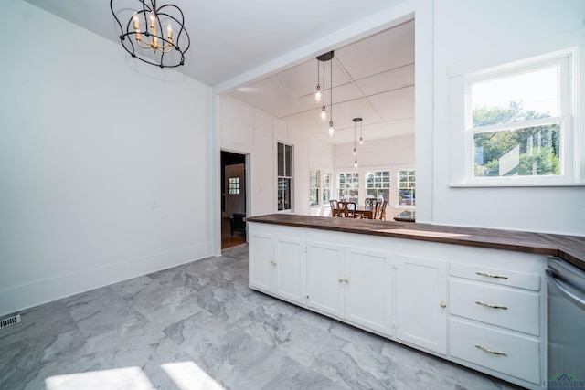 kitchen featuring hanging light fixtures, white cabinets, dishwashing machine, wood counters, and a chandelier