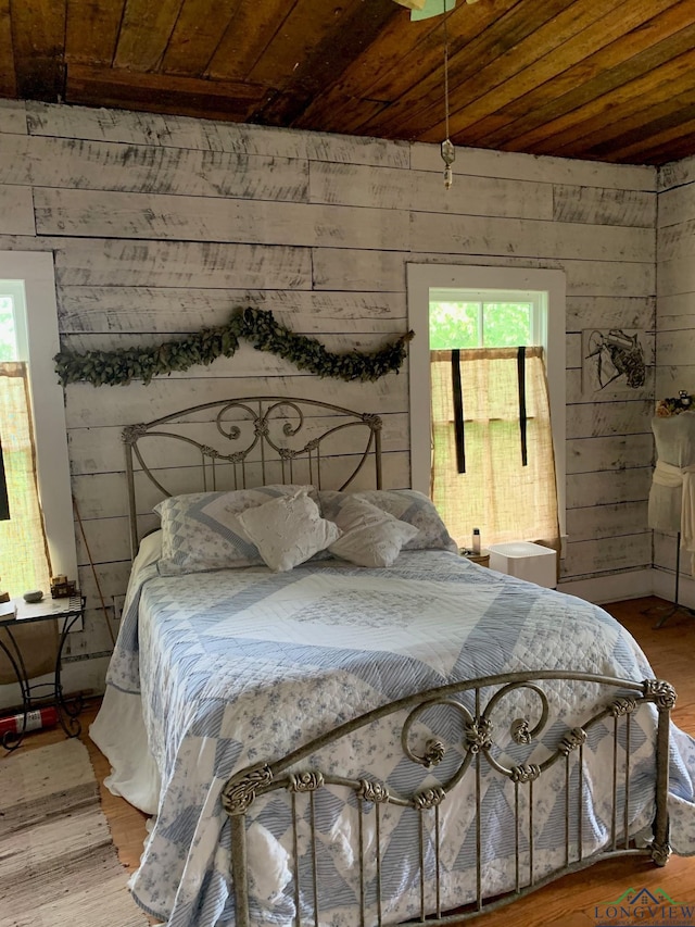 bedroom with wooden ceiling, hardwood / wood-style floors, and wooden walls