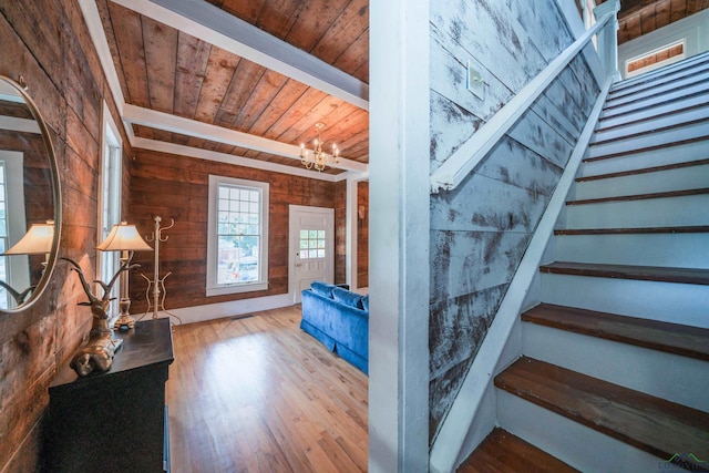 stairway with wooden ceiling, an inviting chandelier, hardwood / wood-style floors, and wooden walls