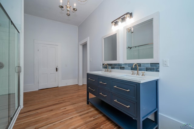 bathroom featuring vanity, hardwood / wood-style floors, decorative backsplash, an inviting chandelier, and an enclosed shower