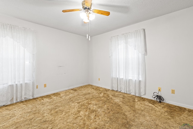 unfurnished room featuring a wealth of natural light, ceiling fan, carpet flooring, and baseboards