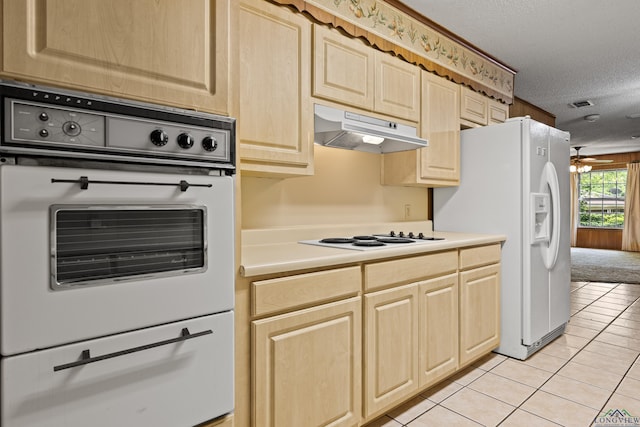 kitchen with white appliances, light brown cabinetry, under cabinet range hood, a textured ceiling, and light tile patterned flooring