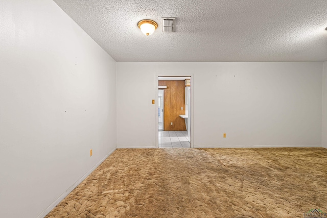 carpeted spare room with baseboards, visible vents, and a textured ceiling