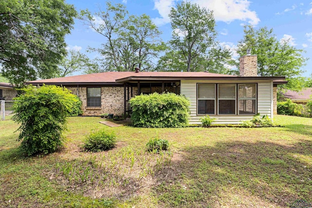 back of house featuring a lawn, fence, and a chimney
