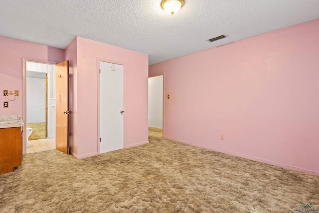 unfurnished bedroom featuring a textured ceiling, visible vents, and carpet floors
