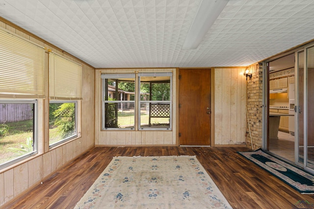 unfurnished sunroom featuring wood-type flooring and wood walls