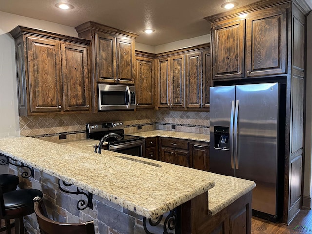 kitchen with a kitchen breakfast bar, kitchen peninsula, and appliances with stainless steel finishes