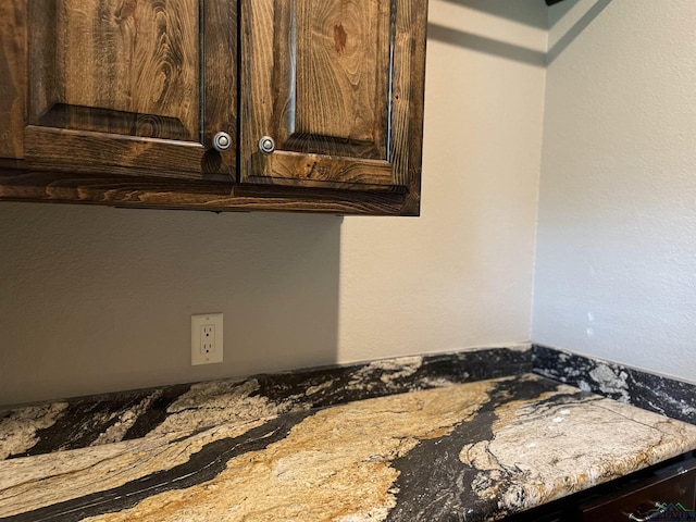 interior details with light stone countertops and dark brown cabinets