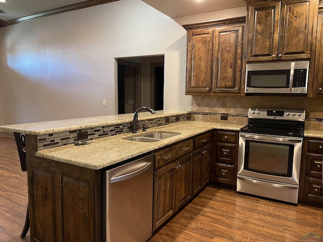 kitchen with kitchen peninsula, a kitchen bar, stainless steel appliances, and sink