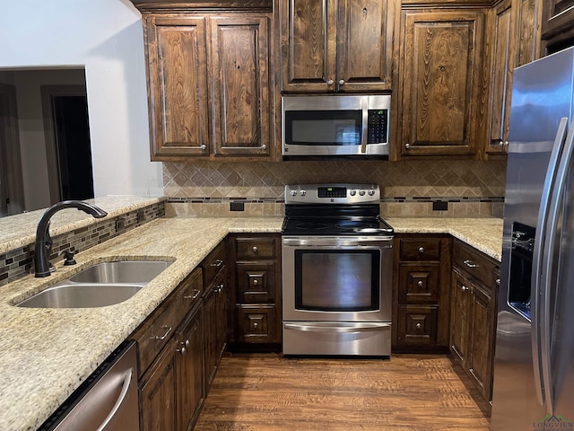 kitchen featuring light stone countertops, appliances with stainless steel finishes, dark brown cabinetry, sink, and dark hardwood / wood-style floors