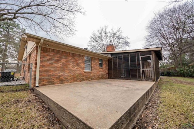 back of property with a sunroom, a chimney, fence, a patio area, and brick siding