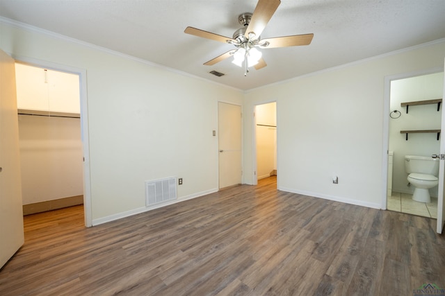 unfurnished bedroom with visible vents, a spacious closet, and wood finished floors